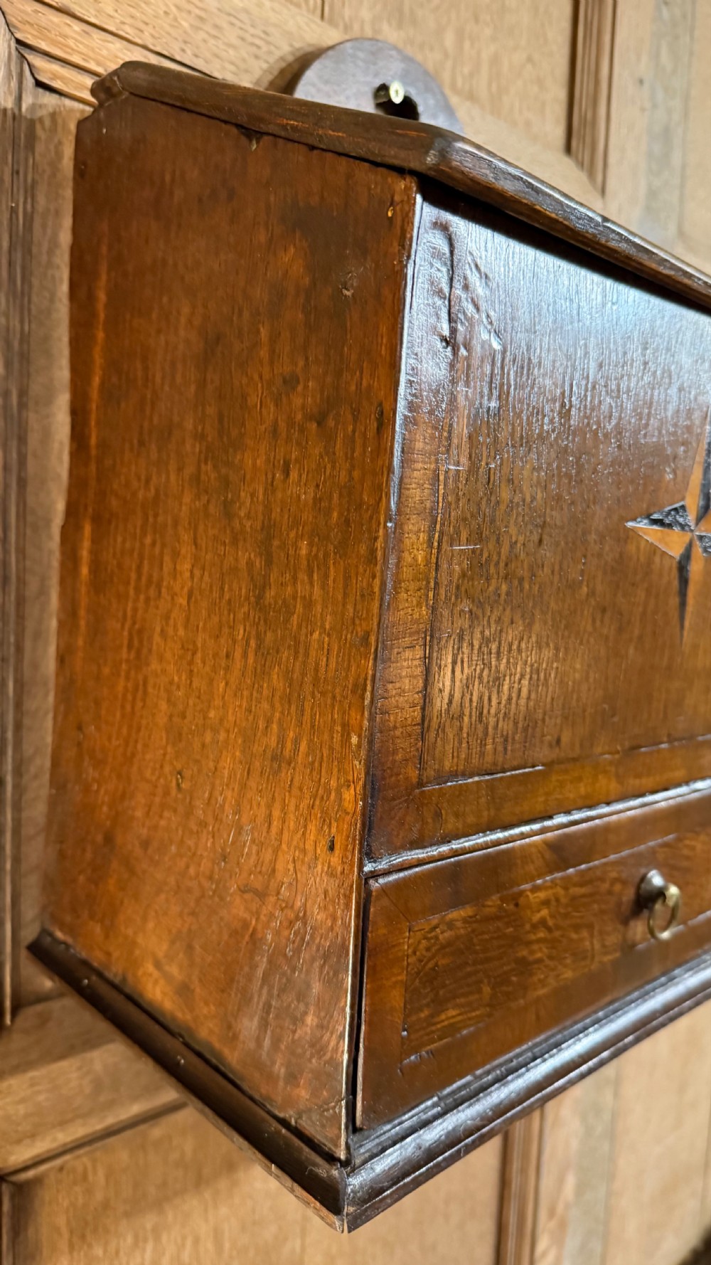 A 19th-century wall-mounted oak box featuring a star marquetry inlay, a heart-shaped hanging cut-out, and a lower drawer with a metal ring pull. View III