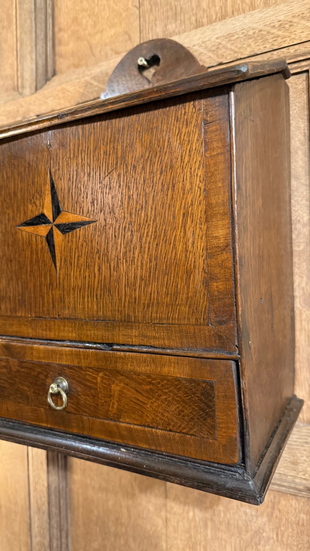 A 19th-century wall-mounted oak box featuring a star marquetry inlay, a heart-shaped hanging cut-out, and a lower drawer with a metal ring pull. View IV