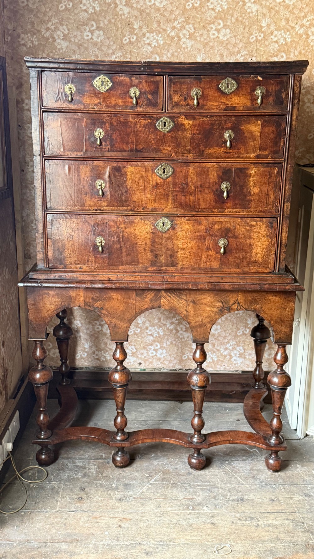 A late 17th-century walnut chest on stand featuring brass drop handles, five drawers, an arched apron, and six turned legs with shaped stretchers. View II
