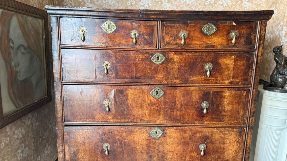 A late 17th-century walnut chest on stand featuring brass drop handles, five drawers, an arched apron, and six turned legs with shaped stretchers. View IV