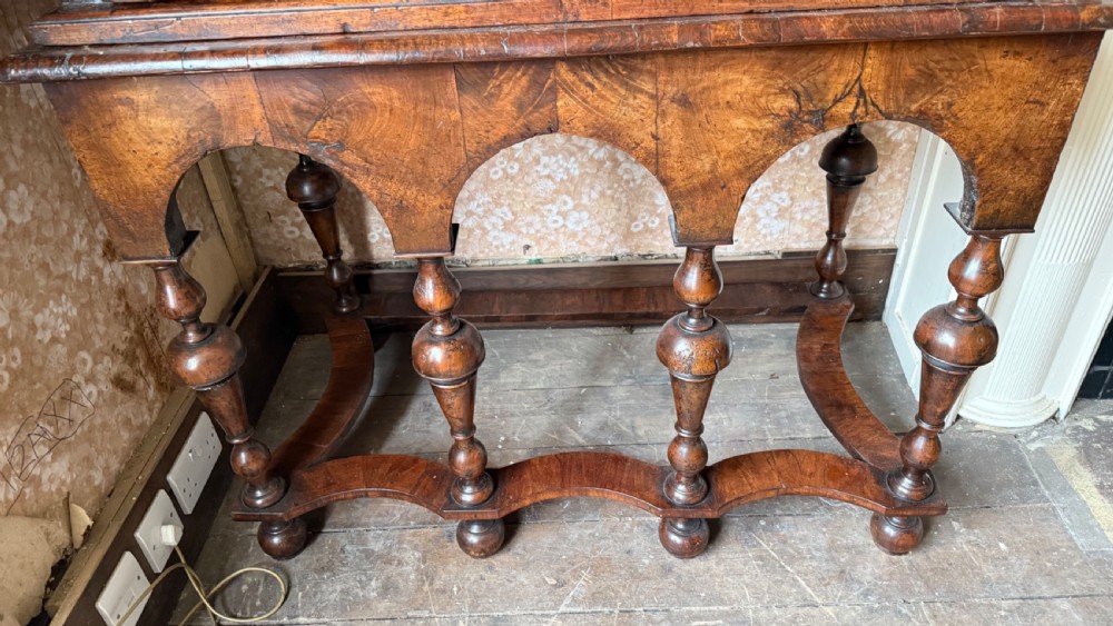 A late 17th-century walnut chest on stand featuring brass drop handles, five drawers, an arched apron, and six turned legs with shaped stretchers. View IX