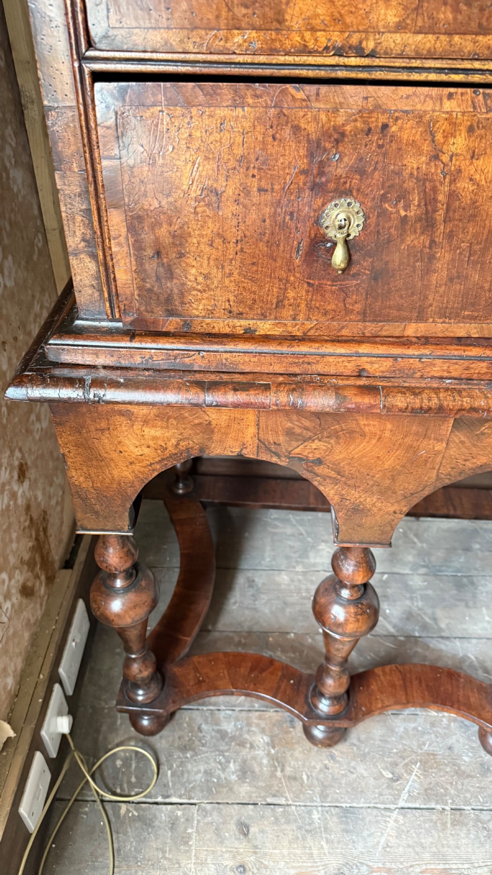 A late 17th-century walnut chest on stand featuring brass drop handles, five drawers, an arched apron, and six turned legs with shaped stretchers. View X