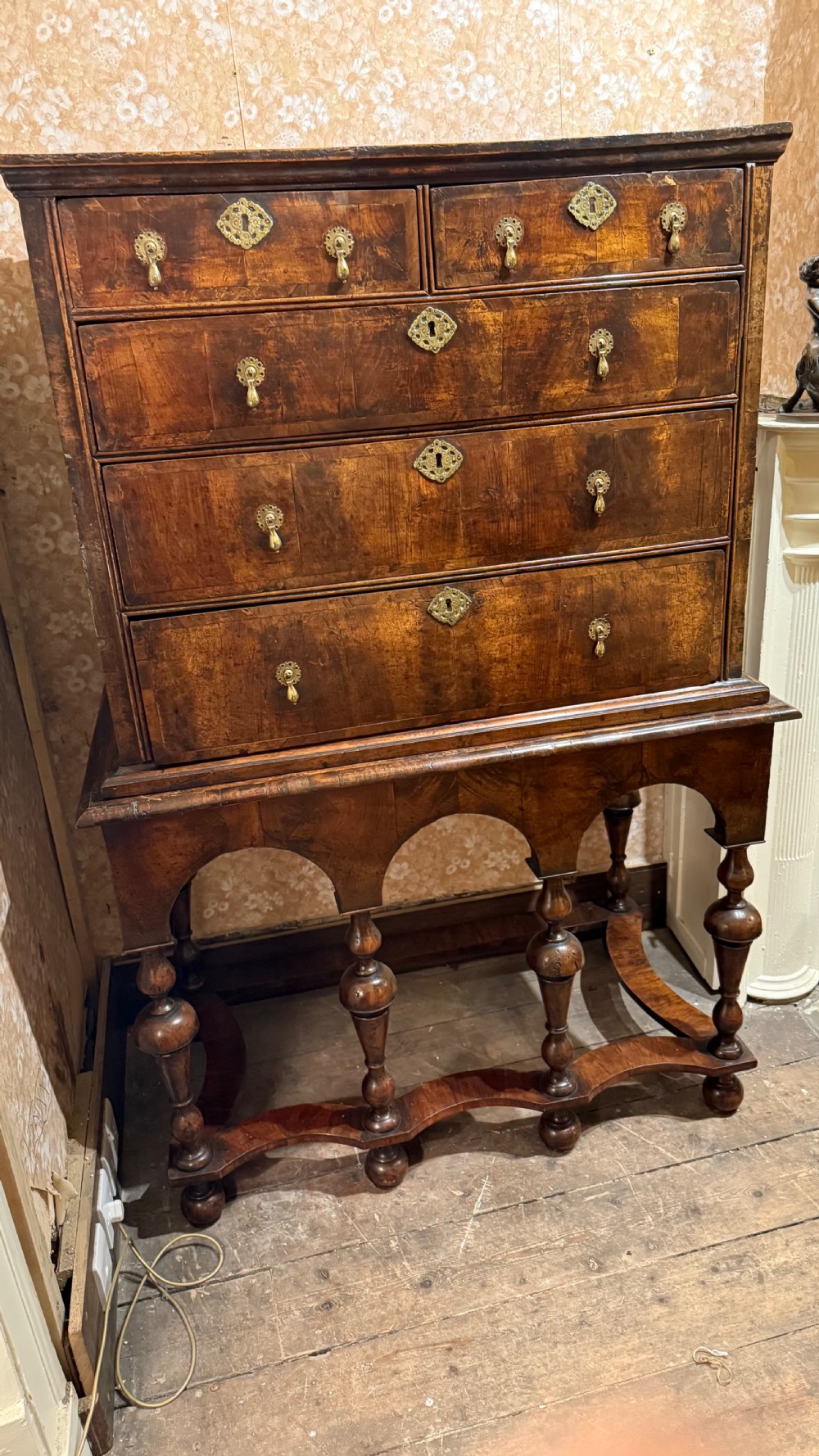 A late 17th-century walnut chest on stand featuring brass drop handles, five drawers, an arched apron, and six turned legs with shaped stretchers. View XVI