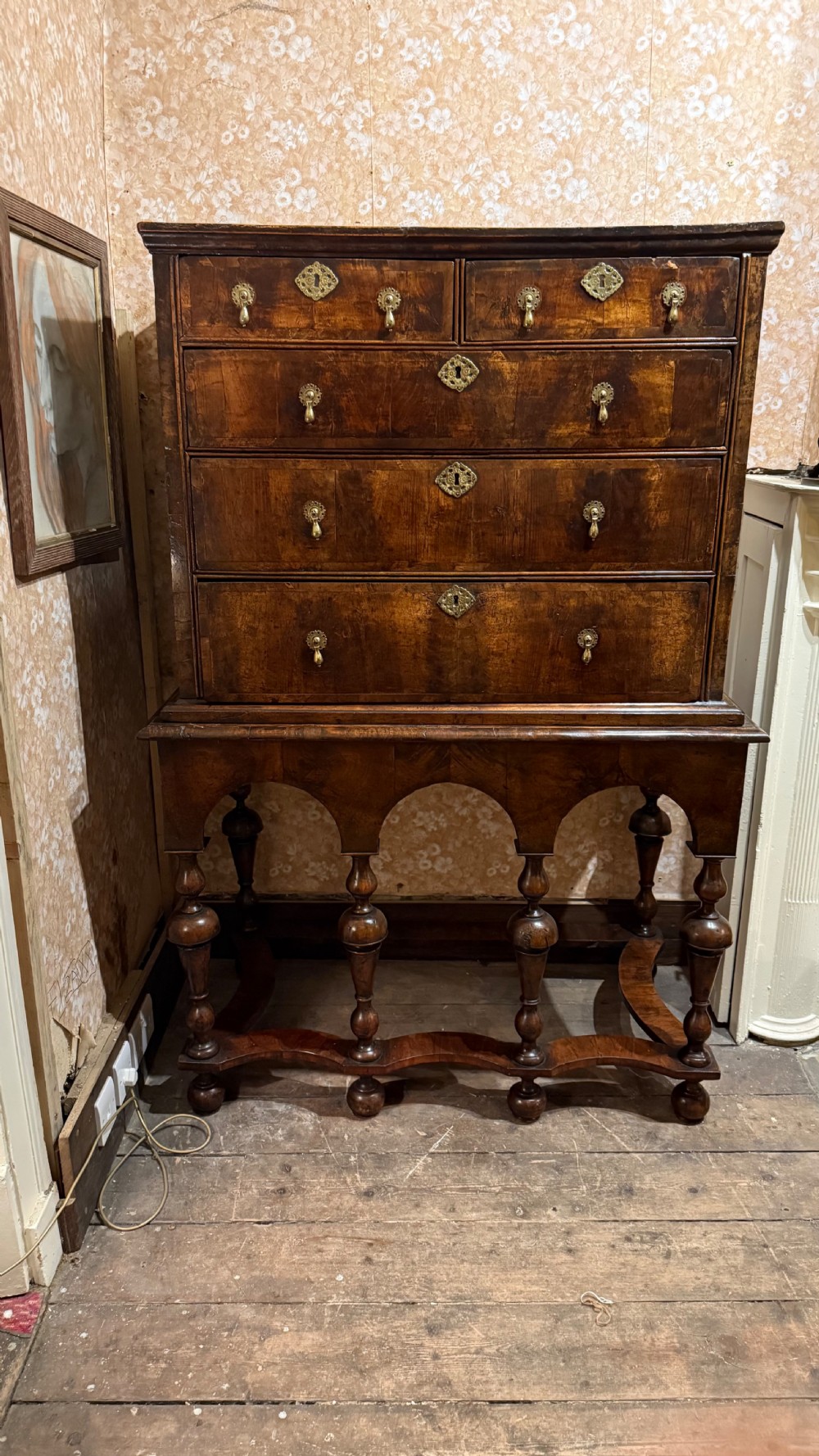 A late 17th-century walnut chest on stand featuring brass drop handles, five drawers, an arched apron, and six turned legs with shaped stretchers. View XVIII