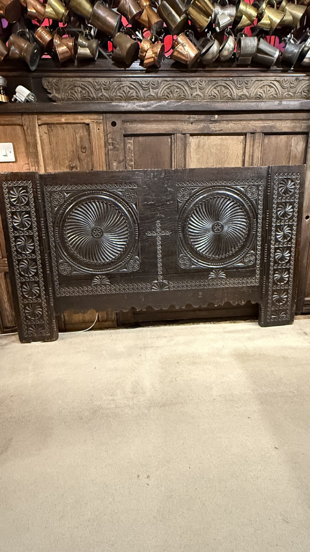 A 16th-century carved dark oak coffer front panel featuring central cross and circular pinwheel motifs with geometric borders.