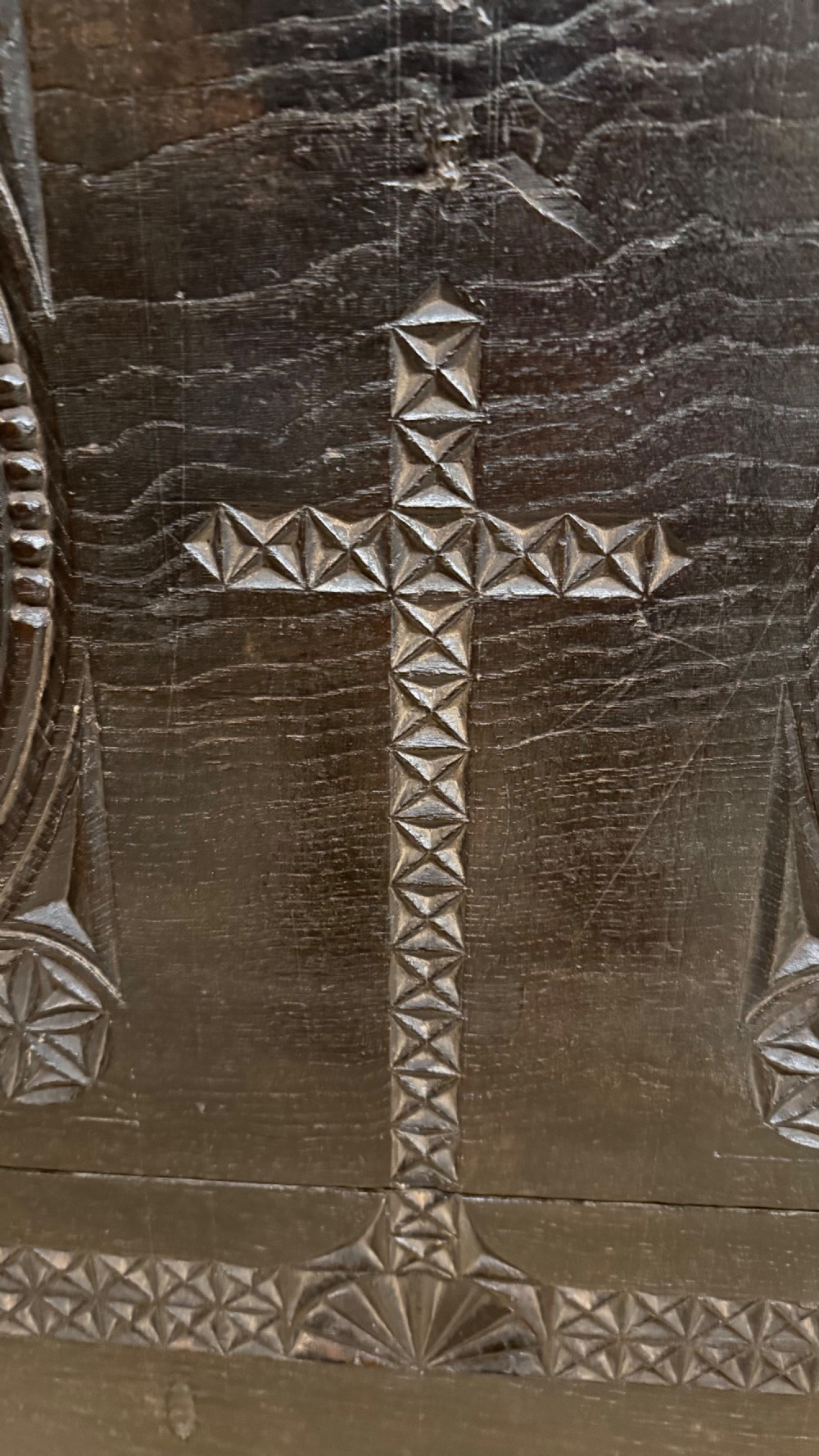 A 16th-century carved dark oak coffer front panel featuring central cross and circular pinwheel motifs with geometric borders. View V