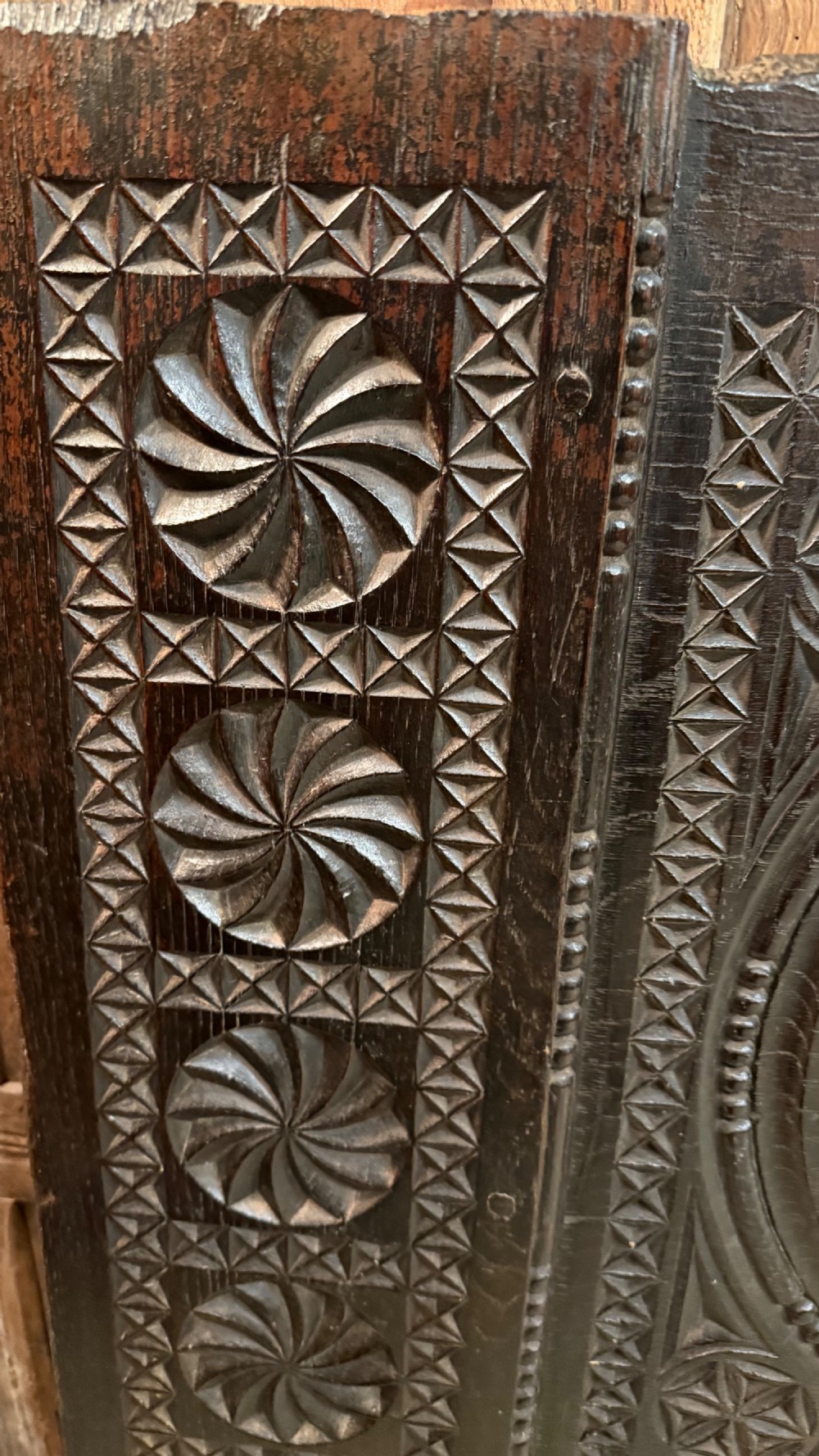 A 16th-century carved dark oak coffer front panel featuring central cross and circular pinwheel motifs with geometric borders. View VI