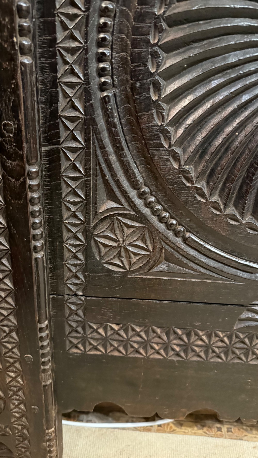 A 16th-century carved dark oak coffer front panel featuring central cross and circular pinwheel motifs with geometric borders. View X