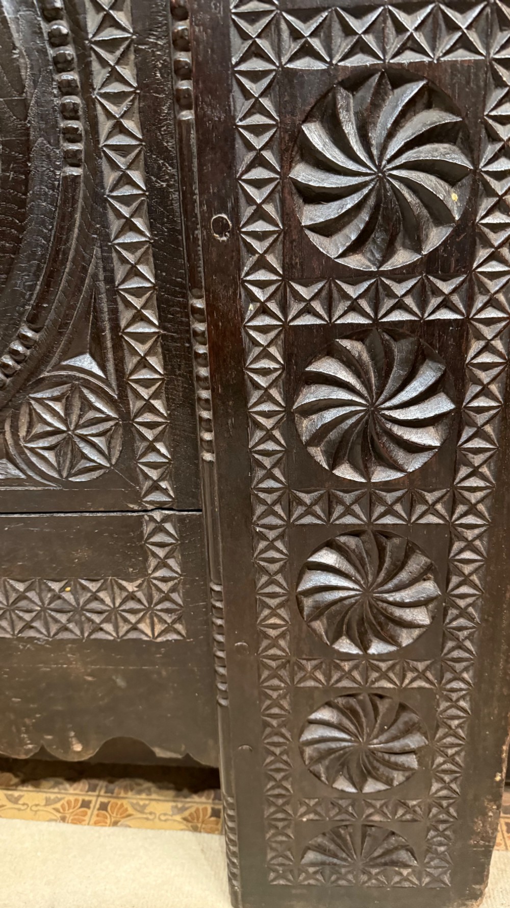 A 16th-century carved dark oak coffer front panel featuring central cross and circular pinwheel motifs with geometric borders. View XII