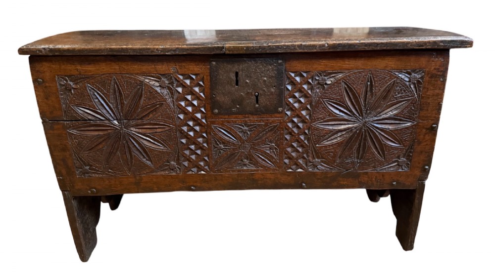 A 16th-century dark oak plank coffer featuring deeply carved floral rosette panels, geometric chip carving, and a central iron lock plate. View II