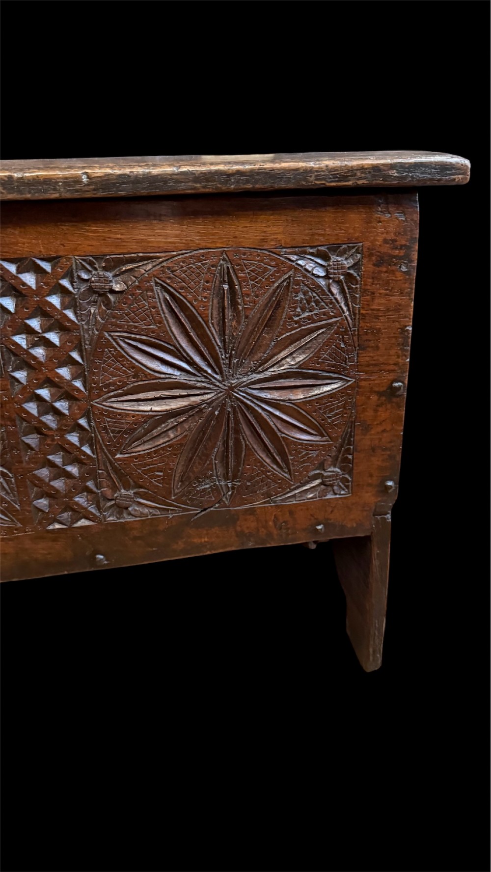 A 16th-century dark oak plank coffer featuring deeply carved floral rosette panels, geometric chip carving, and a central iron lock plate. View VI