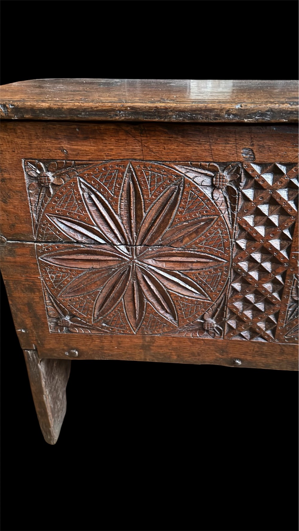 A 16th-century dark oak plank coffer featuring deeply carved floral rosette panels, geometric chip carving, and a central iron lock plate. View VII