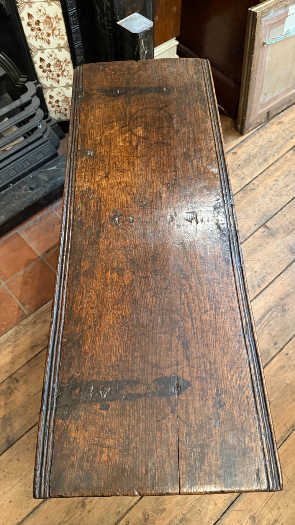 A 16th-century dark oak plank coffer featuring deeply carved floral rosette panels, geometric chip carving, and a central iron lock plate. View XI