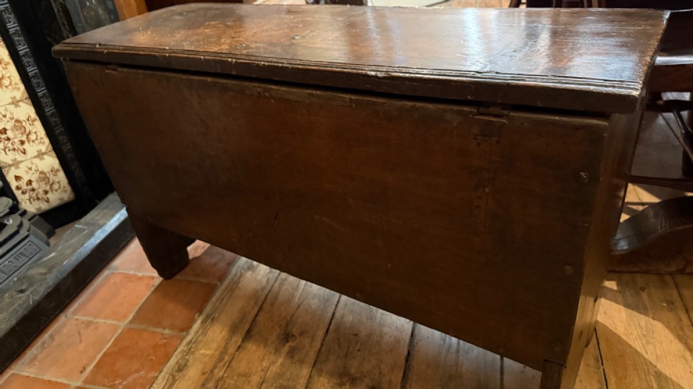 A 16th-century dark oak plank coffer featuring deeply carved floral rosette panels, geometric chip carving, and a central iron lock plate. View XII