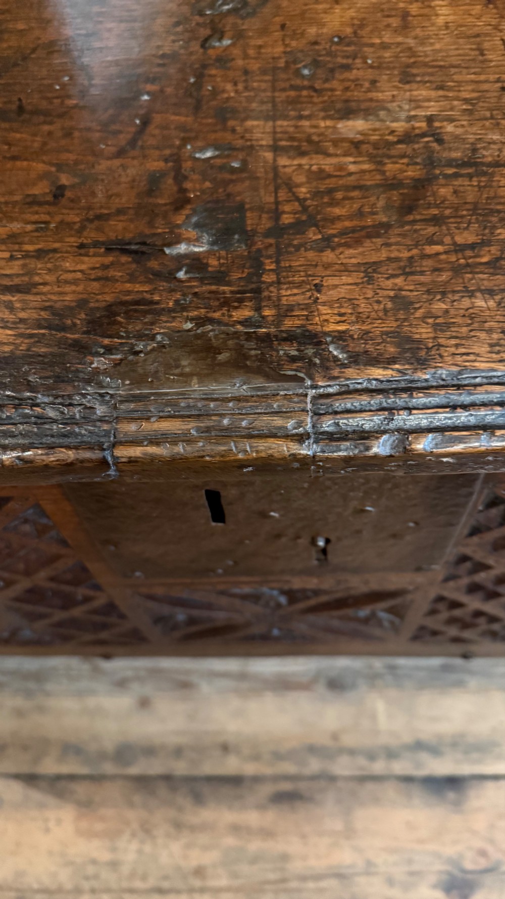 A 16th-century dark oak plank coffer featuring deeply carved floral rosette panels, geometric chip carving, and a central iron lock plate. View XIII