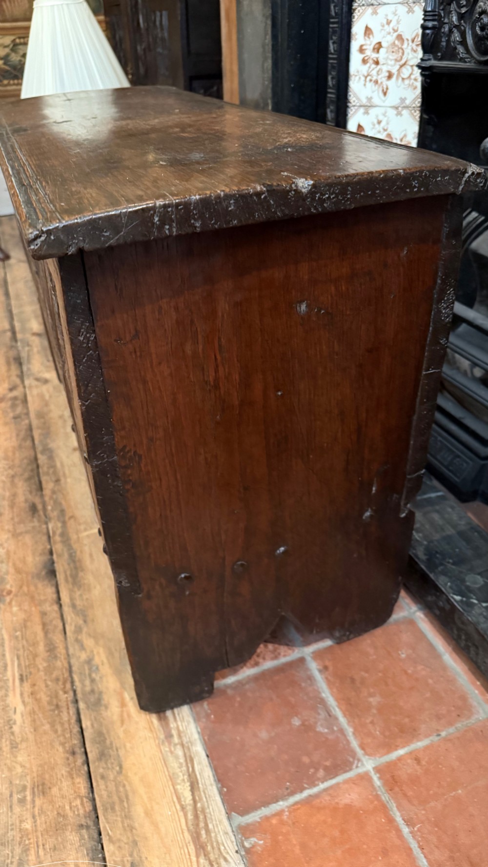 A 16th-century dark oak plank coffer featuring deeply carved floral rosette panels, geometric chip carving, and a central iron lock plate. View XV