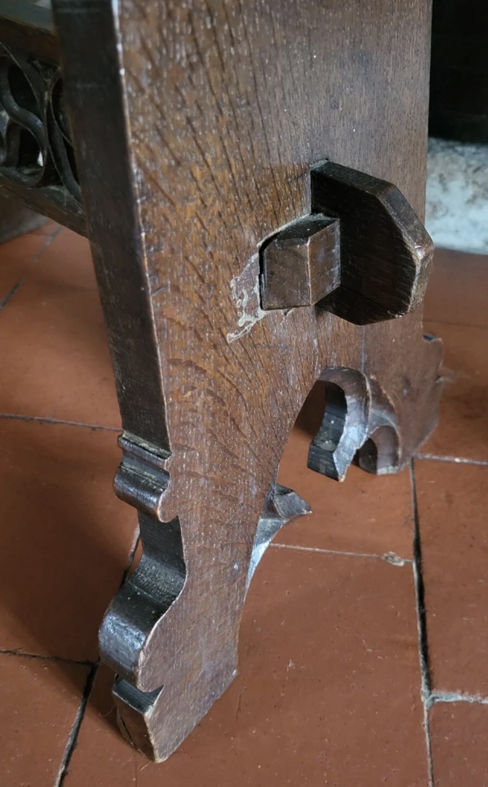 A 19th-century dark oak Gothic Revival stool featuring carved tracery cut-outs on the slab legs, a carved central stretcher, and a carved recessed motif on the top. View VIII