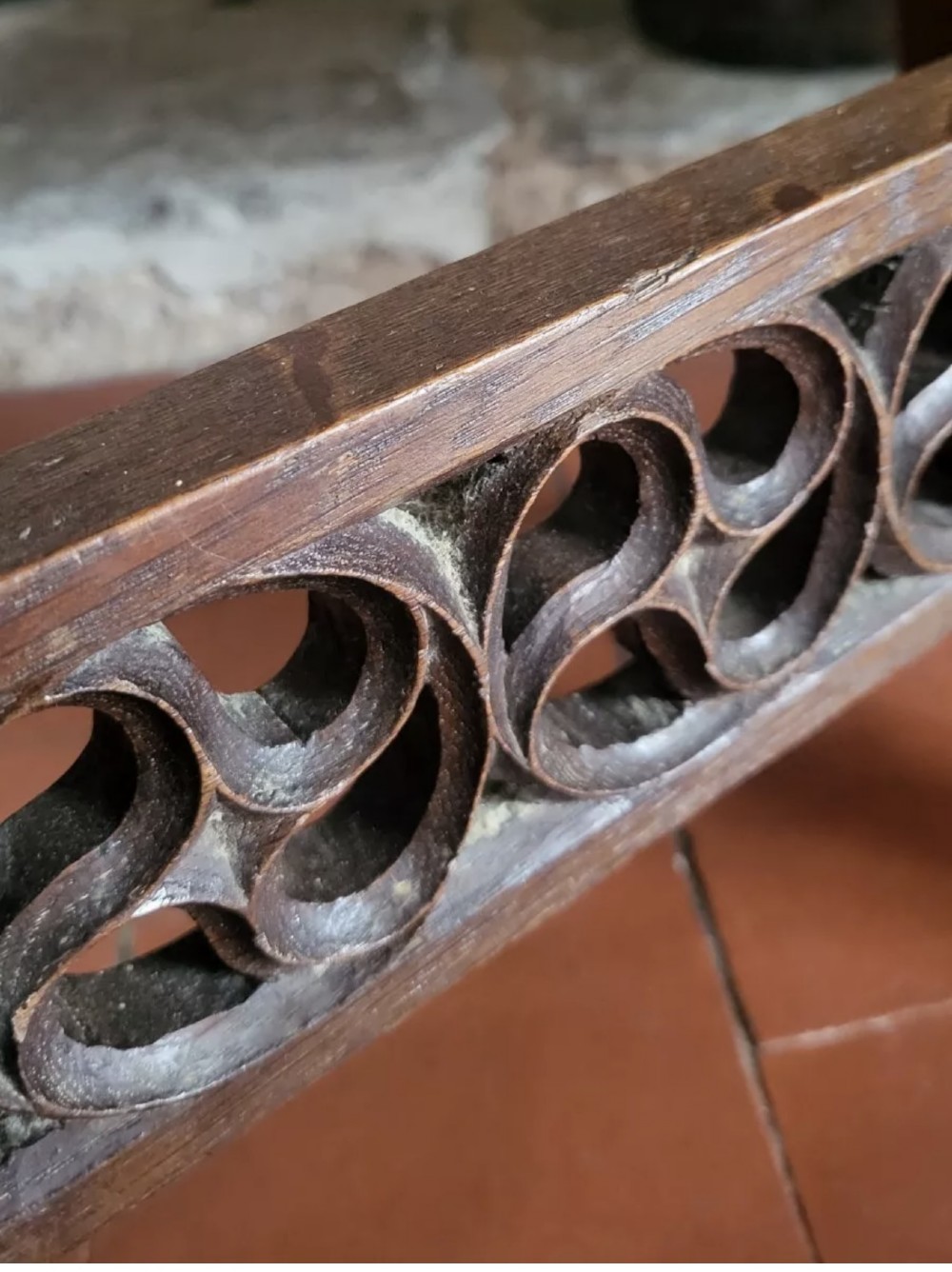 A 19th-century dark oak Gothic Revival stool featuring carved tracery cut-outs on the slab legs, a carved central stretcher, and a carved recessed motif on the top. View IX
