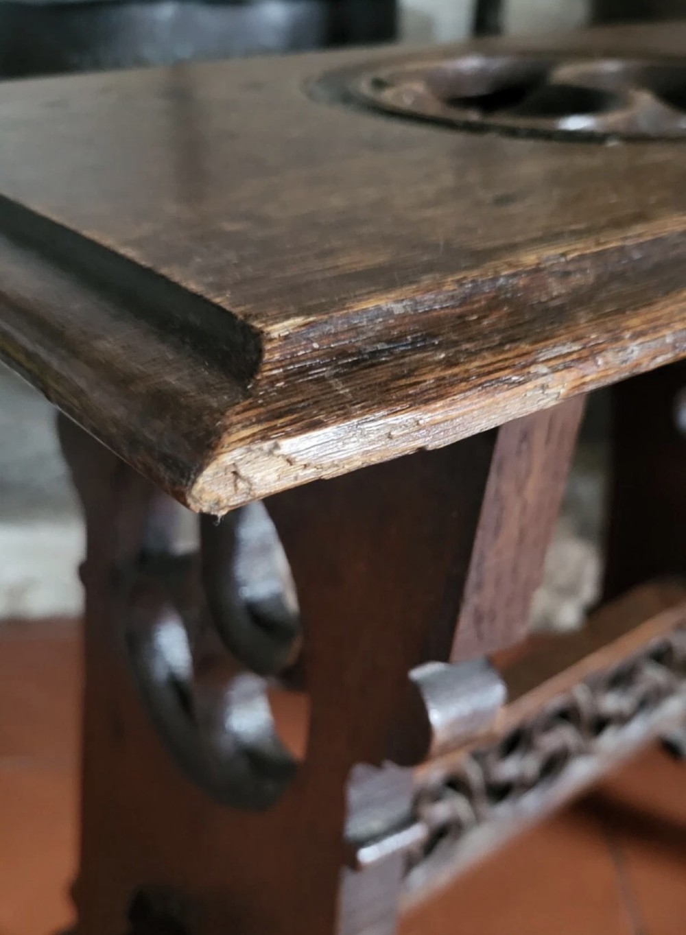 A 19th-century dark oak Gothic Revival stool featuring carved tracery cut-outs on the slab legs, a carved central stretcher, and a carved recessed motif on the top. View XII