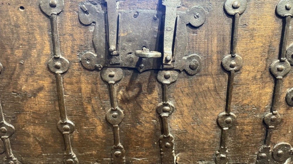 A sixteenth-century rectangular dark wood casket bound with riveted iron straps, featuring a top carrying handle and arched timber base. View II