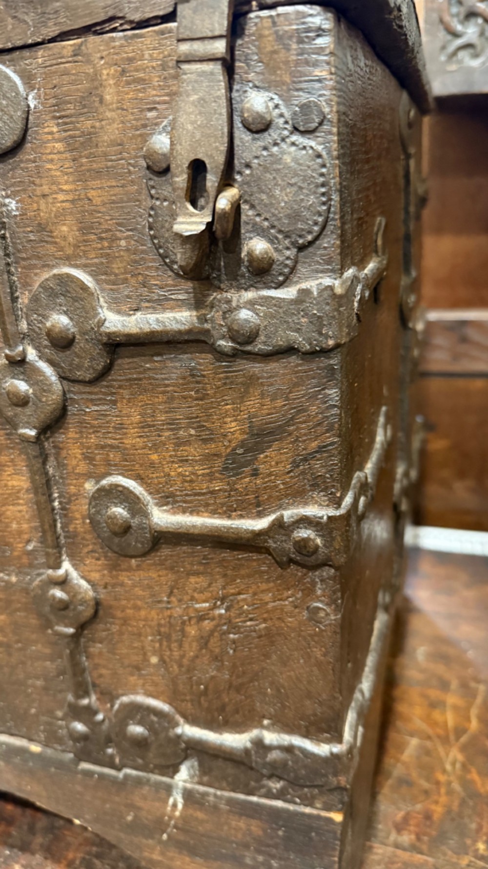 A sixteenth-century rectangular dark wood casket bound with riveted iron straps, featuring a top carrying handle and arched timber base. View V