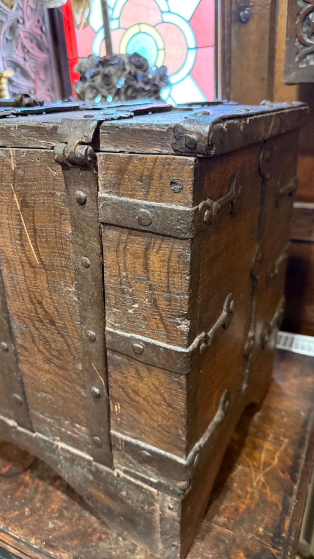 A sixteenth-century rectangular dark wood casket bound with riveted iron straps, featuring a top carrying handle and arched timber base. View VI