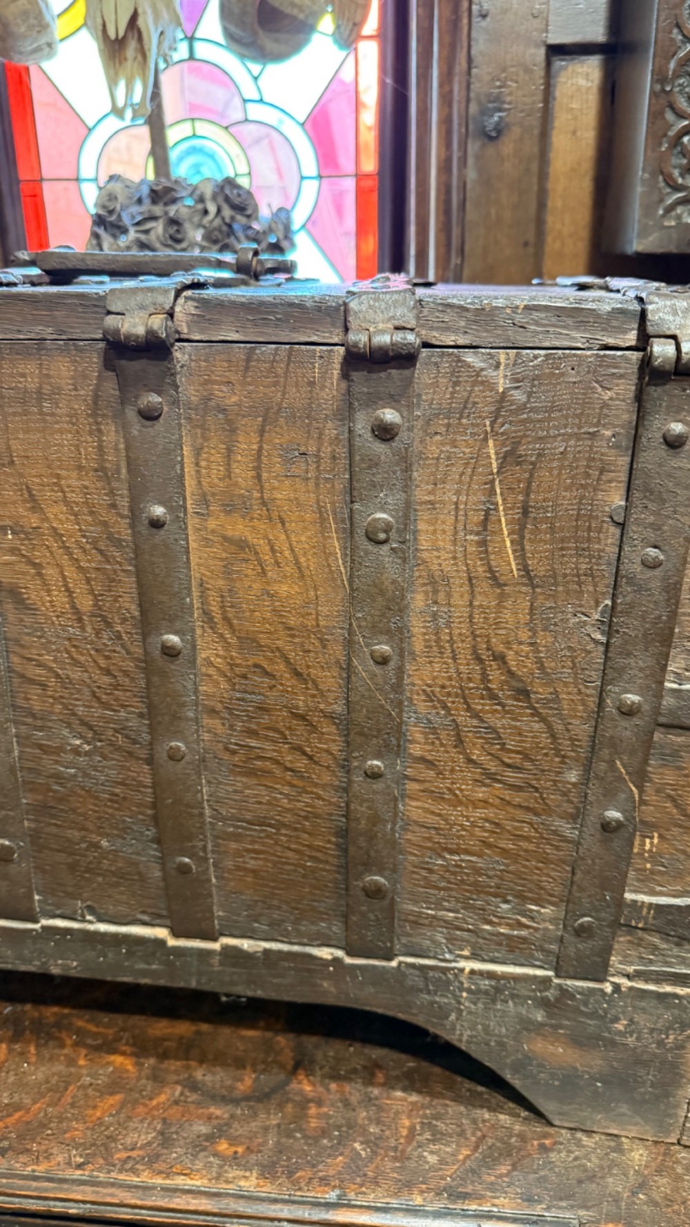 A sixteenth-century rectangular dark wood casket bound with riveted iron straps, featuring a top carrying handle and arched timber base. View VII