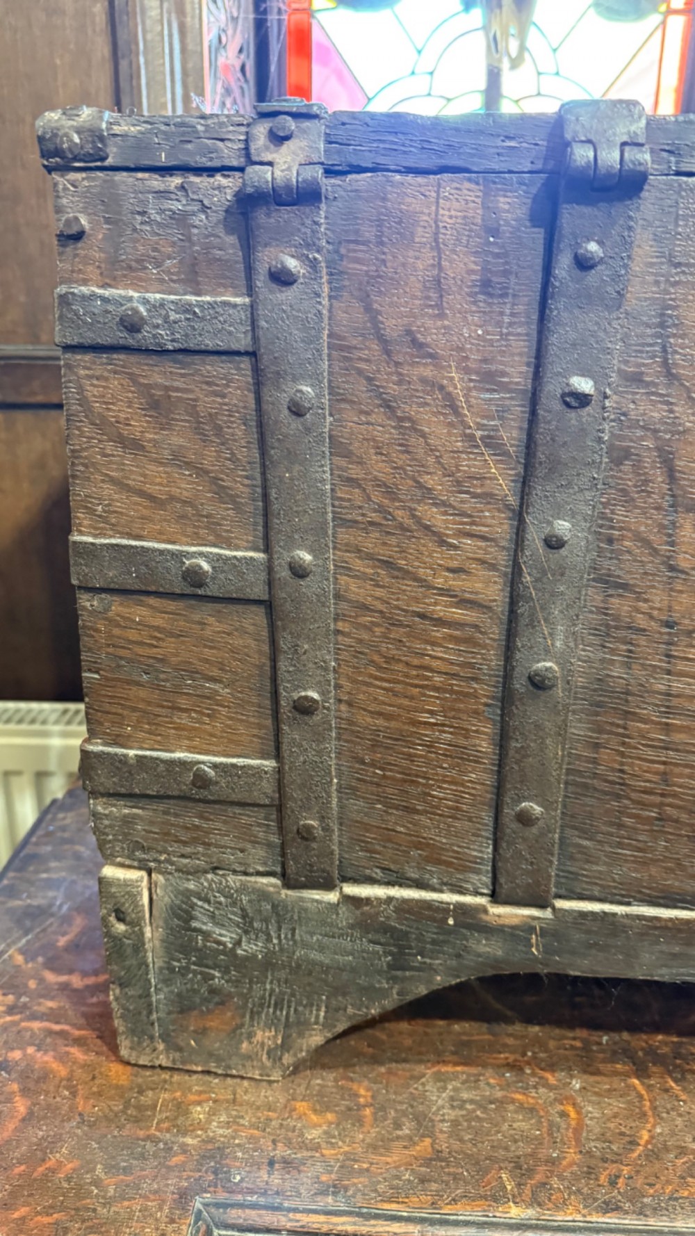 A sixteenth-century rectangular dark wood casket bound with riveted iron straps, featuring a top carrying handle and arched timber base. View VIII