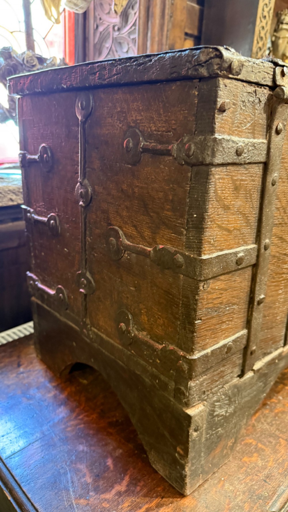 A sixteenth-century rectangular dark wood casket bound with riveted iron straps, featuring a top carrying handle and arched timber base. View IX