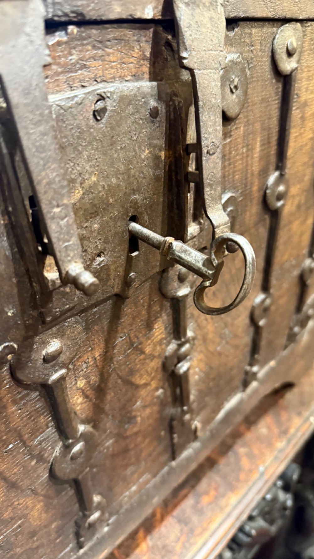 A sixteenth-century rectangular dark wood casket bound with riveted iron straps, featuring a top carrying handle and arched timber base. View XIII