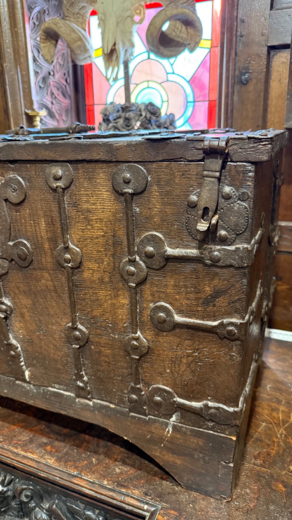 A sixteenth-century rectangular dark wood casket bound with riveted iron straps, featuring a top carrying handle and arched timber base. View XIV