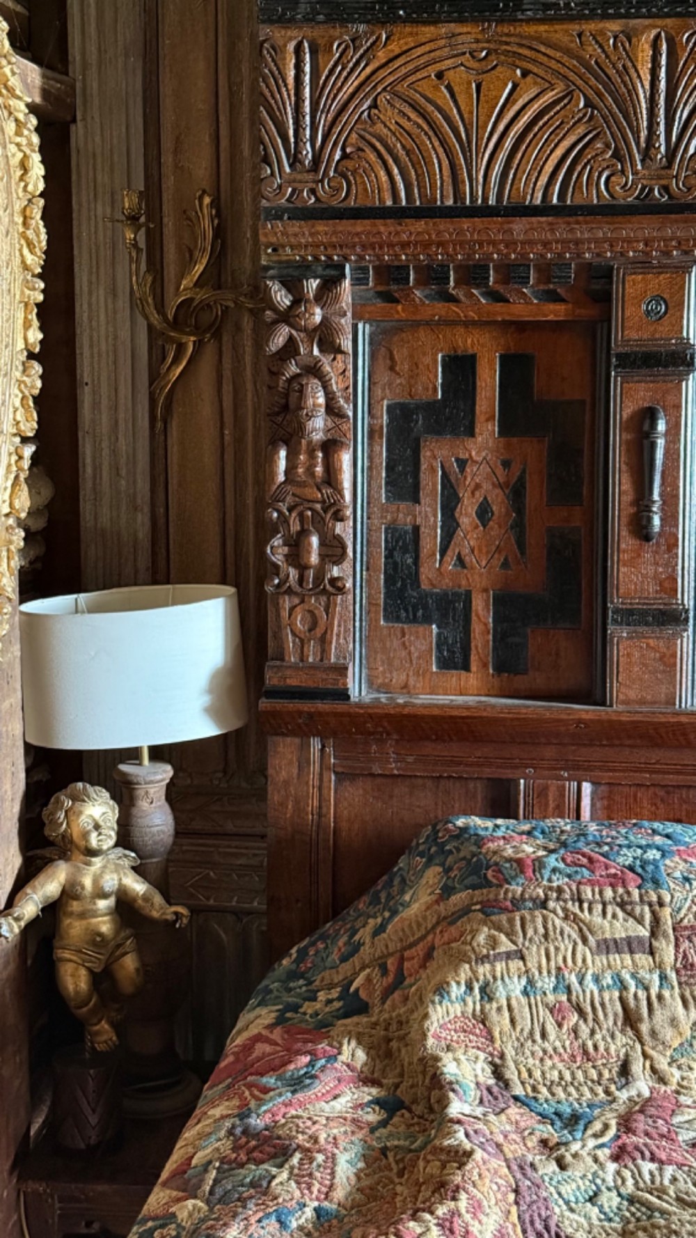 A 17th-century English oak tester bed featuring a heavy panelled canopy, carved geometric headboard, and turned wooden posts. View II