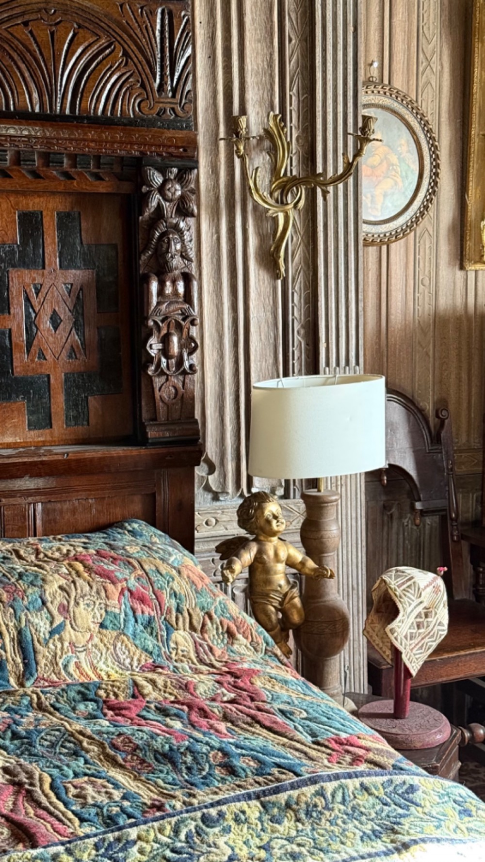 A 17th-century English oak tester bed featuring a heavy panelled canopy, carved geometric headboard, and turned wooden posts. View III