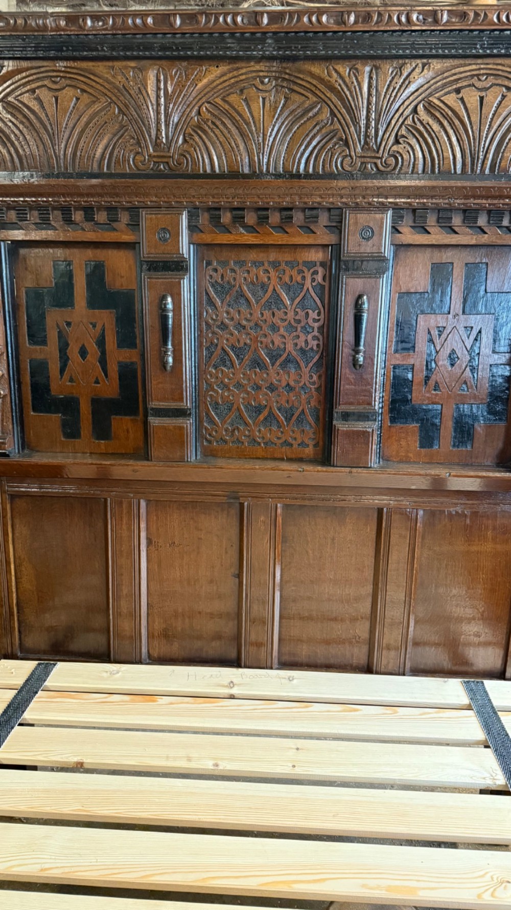 A 17th-century English oak tester bed featuring a heavy panelled canopy, carved geometric headboard, and turned wooden posts. View XII