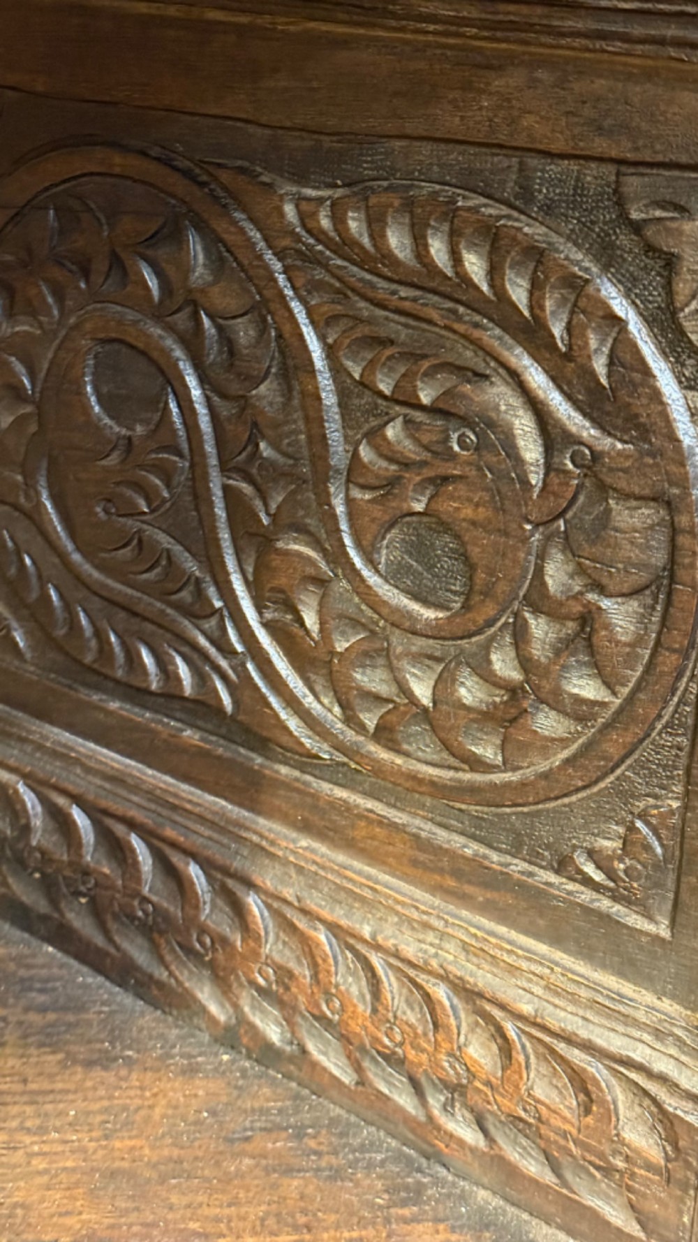 A 17th-century style dark carved oak livery cupboard featuring ornate relief carving, a central face motif panel, turned supports, and an open lower shelf. View XI