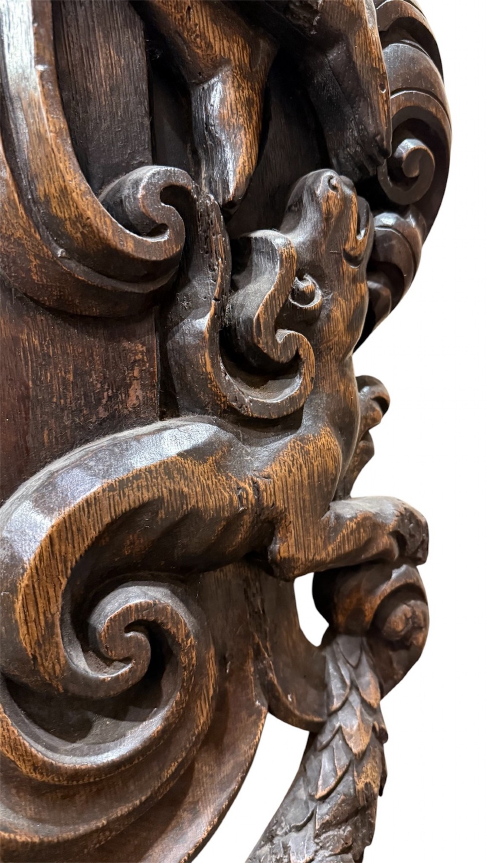 An 18th century dark carved oak wall mirror featuring carved cherubs and scrolling motifs framing an oval mirror plate. View VI