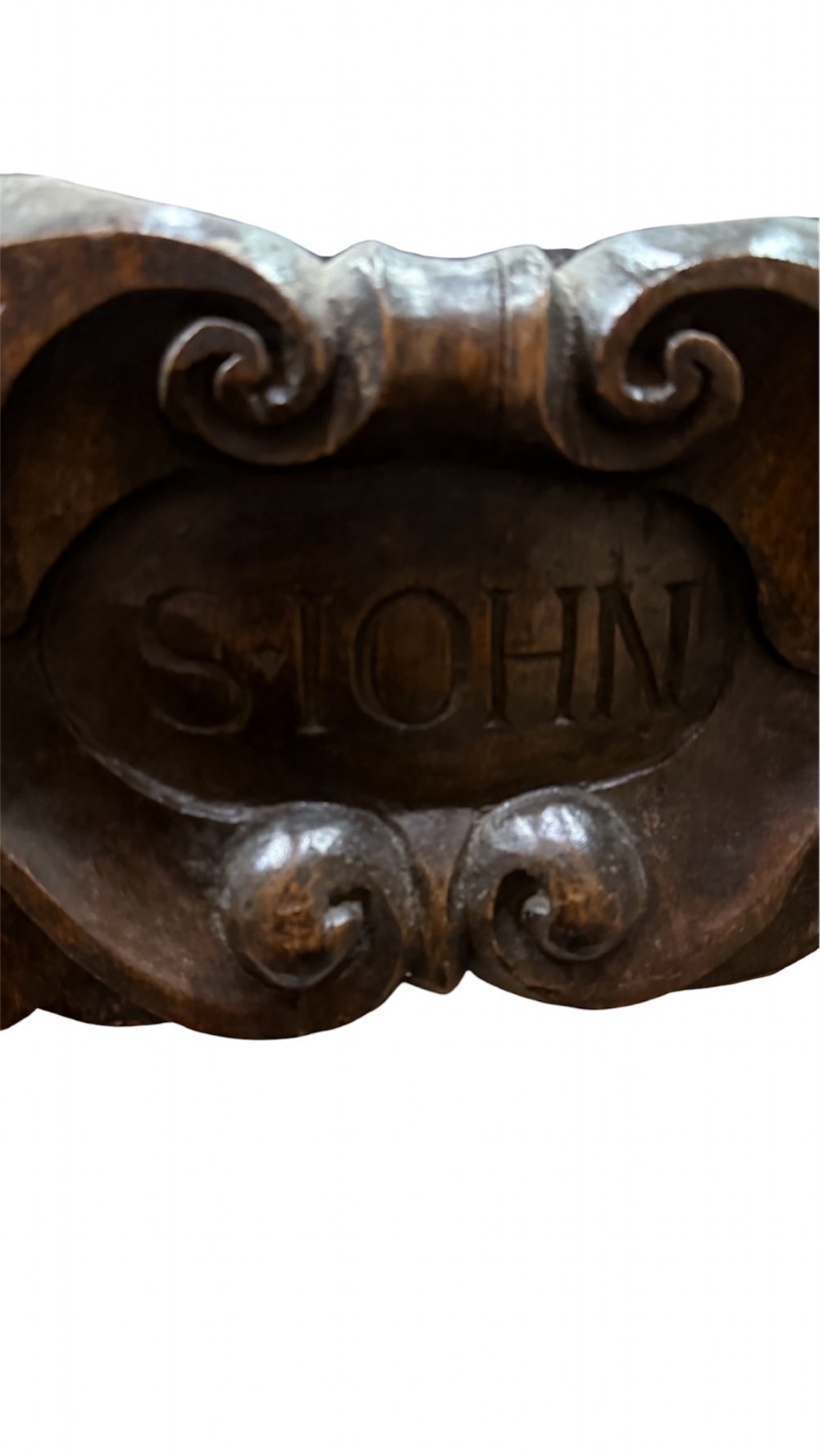 An 18th century dark carved oak wall mirror featuring carved cherubs and scrolling motifs framing an oval mirror plate. View XIII