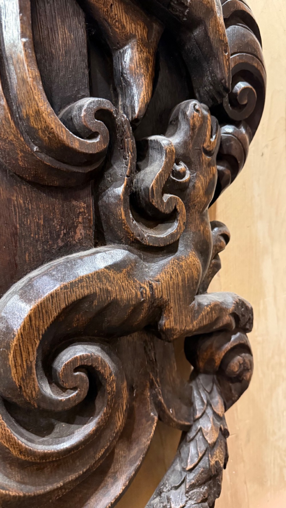An 18th century dark carved oak wall mirror featuring carved cherubs and scrolling motifs framing an oval mirror plate. View XIV