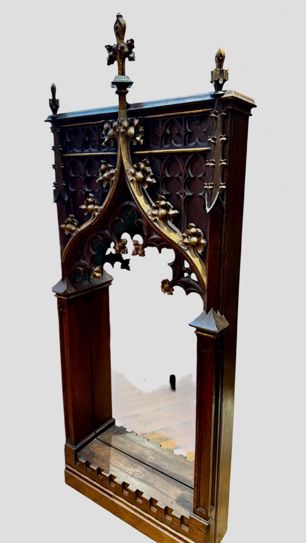 A dark carved oak Gothic Revival mirror frame featuring a pointed arch, intricate tracery, gilded crockets, and decorative finials. View II