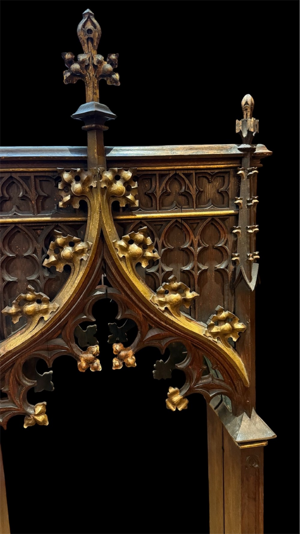 A dark carved oak Gothic Revival mirror frame featuring a pointed arch, intricate tracery, gilded crockets, and decorative finials. View IV
