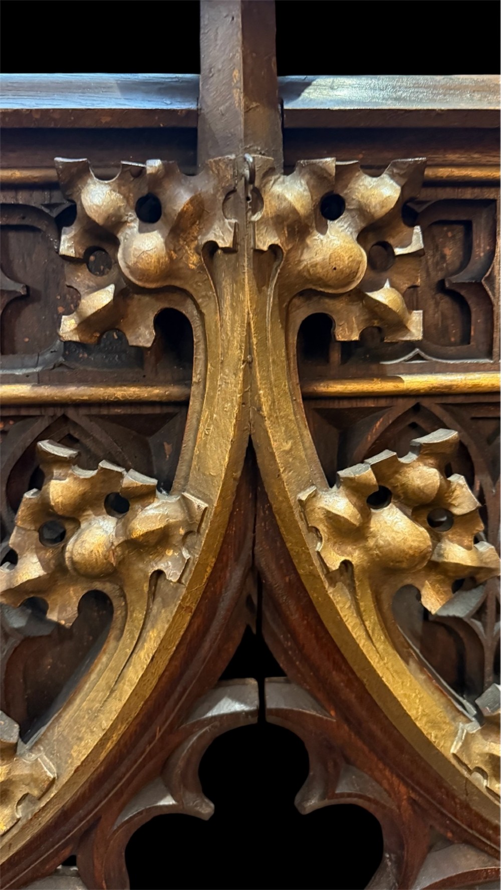 A dark carved oak Gothic Revival mirror frame featuring a pointed arch, intricate tracery, gilded crockets, and decorative finials. View VI