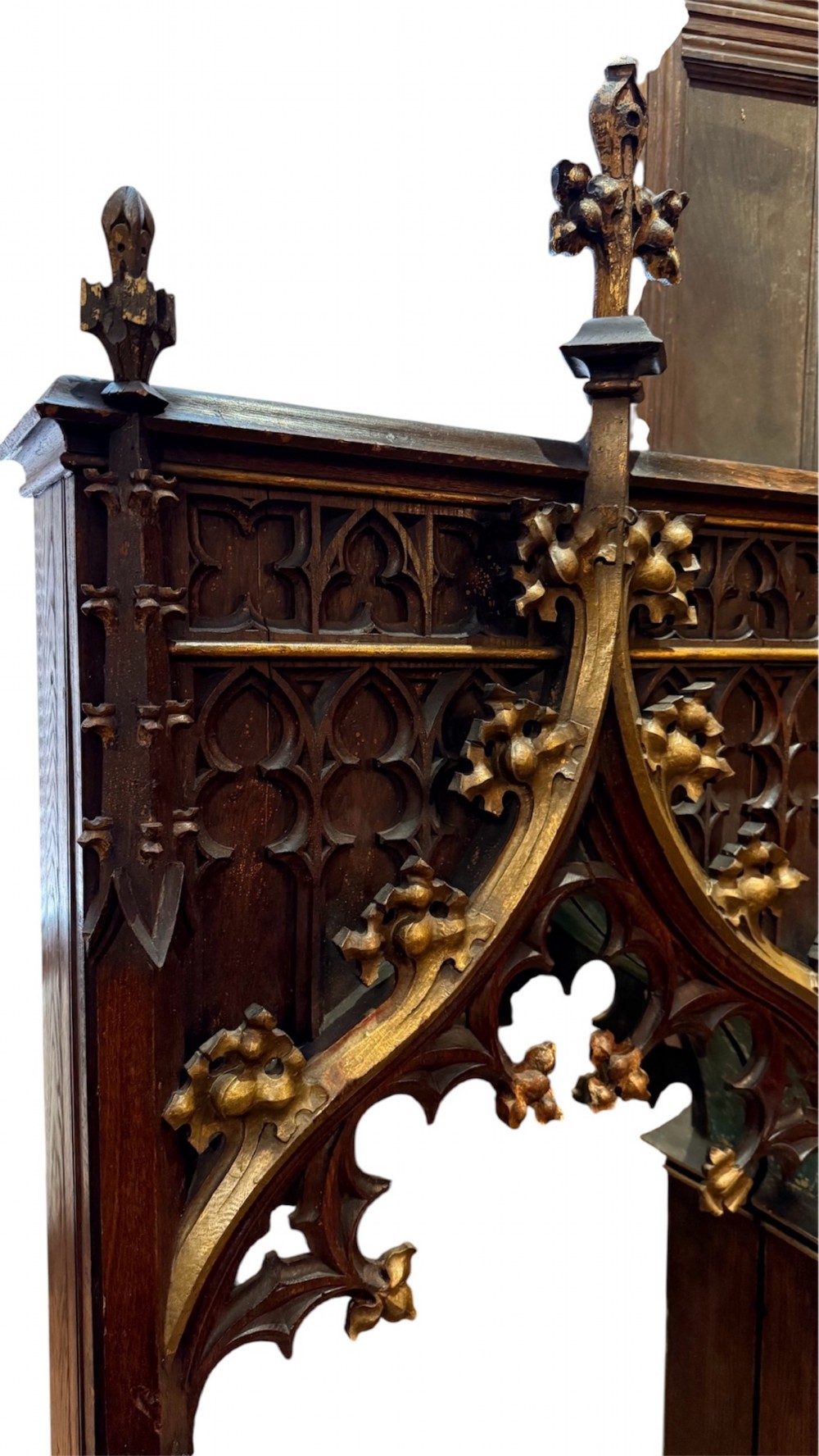 A dark carved oak Gothic Revival mirror frame featuring a pointed arch, intricate tracery, gilded crockets, and decorative finials. View VII