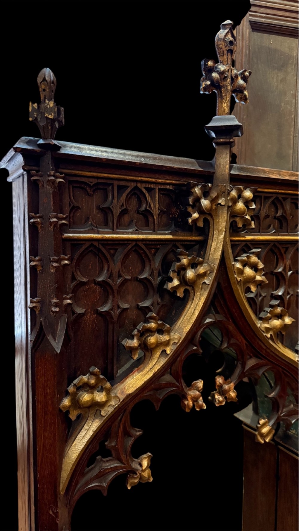 A dark carved oak Gothic Revival mirror frame featuring a pointed arch, intricate tracery, gilded crockets, and decorative finials. View IX