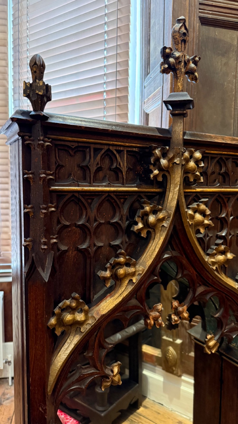 A dark carved oak Gothic Revival mirror frame featuring a pointed arch, intricate tracery, gilded crockets, and decorative finials. View XII