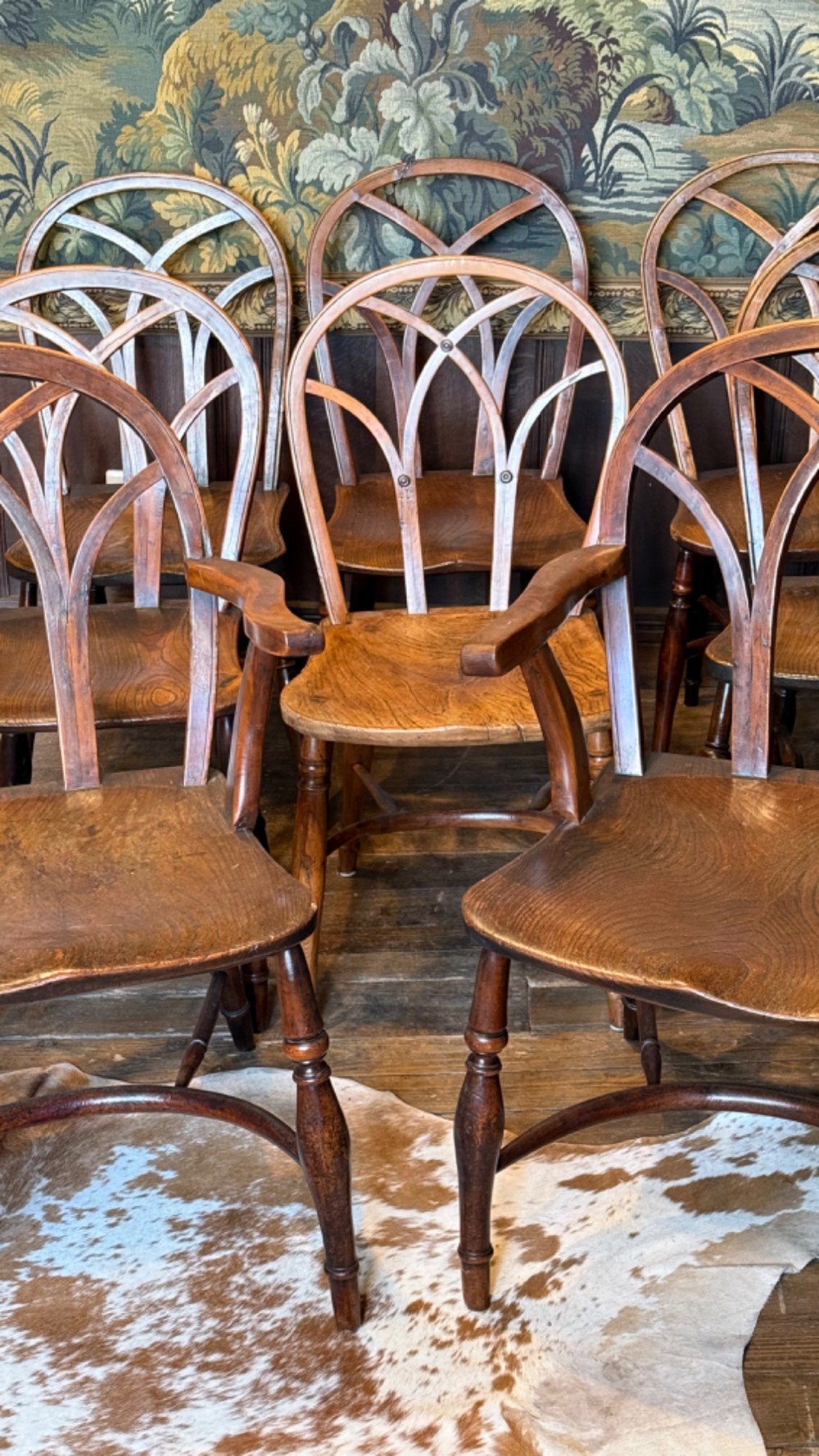 A set of 19th-century Gothic Windsor wooden dining chairs featuring pointed arch back splats, saddle seats, and turned legs. View V