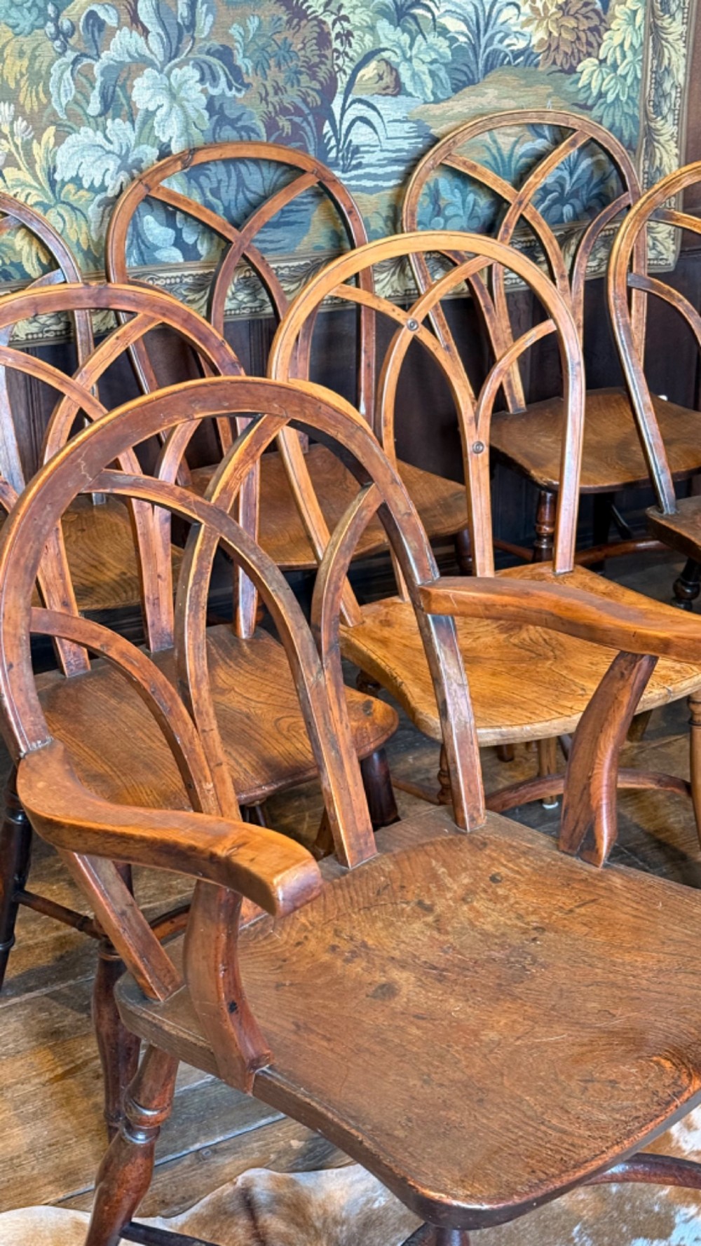 A set of 19th-century Gothic Windsor wooden dining chairs featuring pointed arch back splats, saddle seats, and turned legs. View VI
