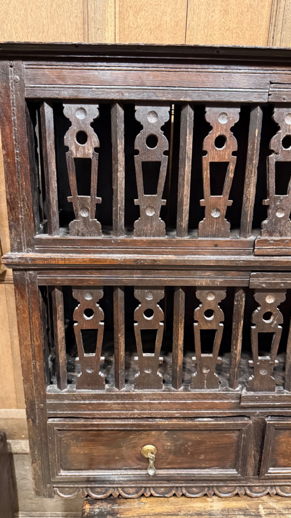 A dark oak seventeenth-century hanging cupboard featuring two upper tiers with carved pierced balusters and three small drawers with teardrop handles along the base. View II