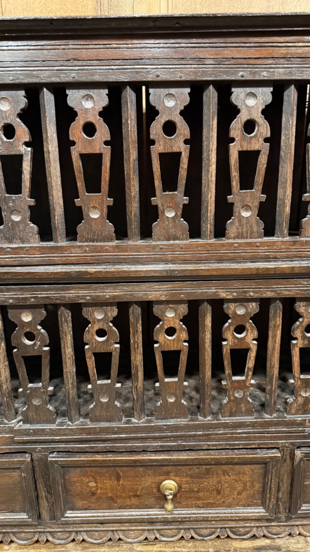 A dark oak seventeenth-century hanging cupboard featuring two upper tiers with carved pierced balusters and three small drawers with teardrop handles along the base. View V
