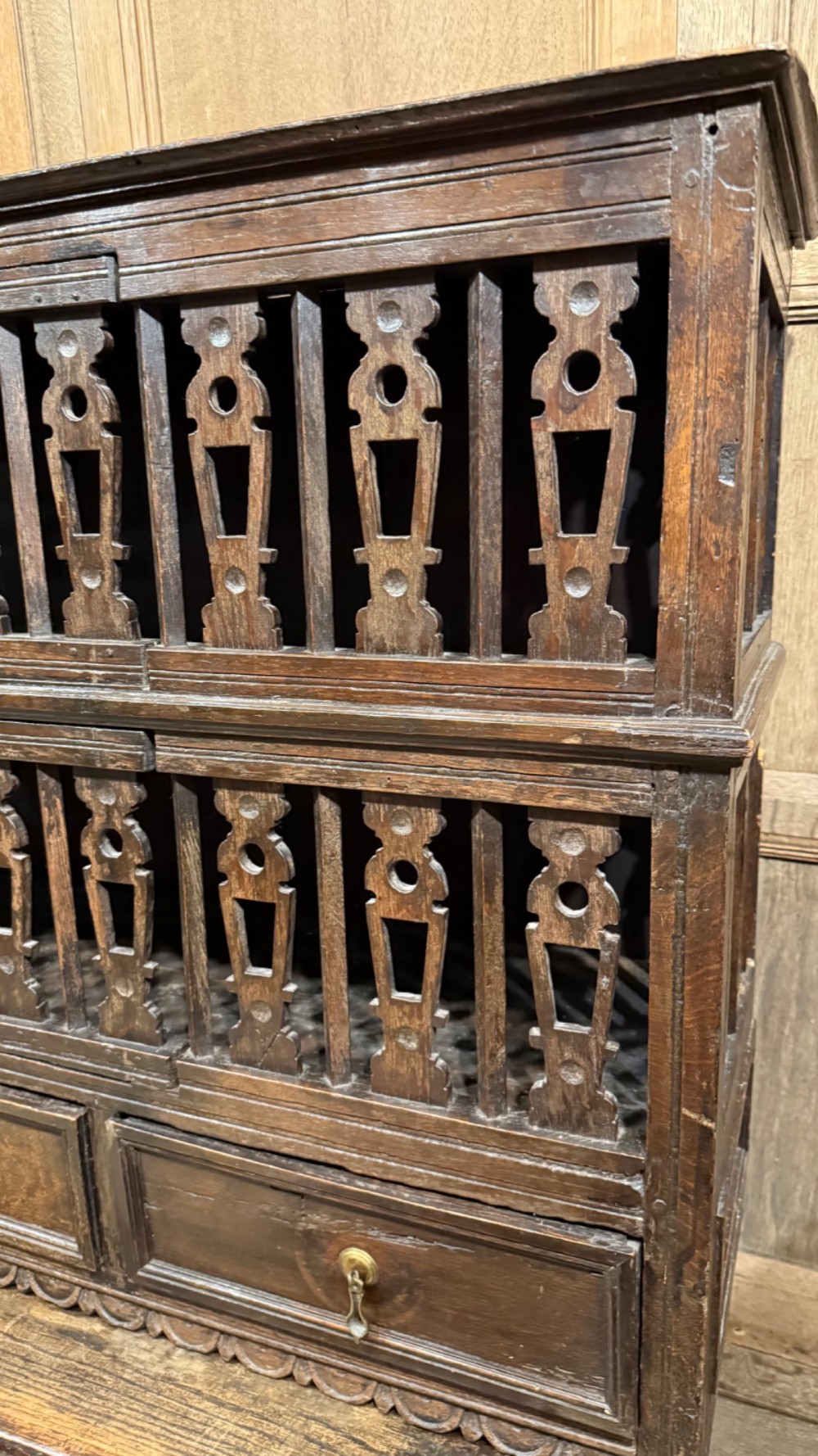 A dark oak seventeenth-century hanging cupboard featuring two upper tiers with carved pierced balusters and three small drawers with teardrop handles along the base. View VI