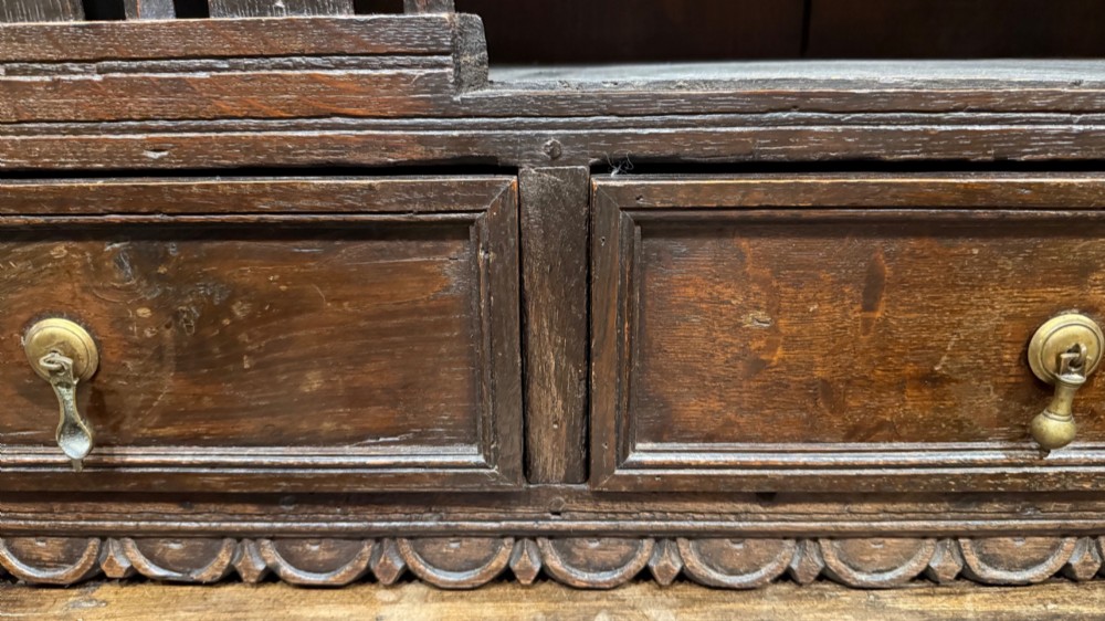 A dark oak seventeenth-century hanging cupboard featuring two upper tiers with carved pierced balusters and three small drawers with teardrop handles along the base. View IX